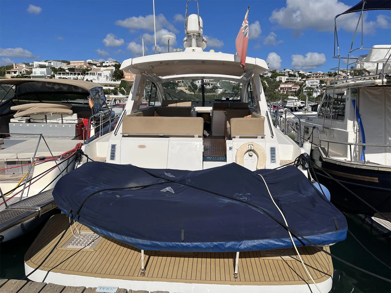 2012 Sealine SC47 yacht docked at marina under blue sky.