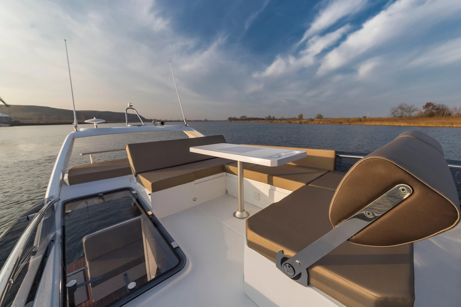 2025 Galeon 360 Fly yacht deck with seating and table, cruising on a calm river.