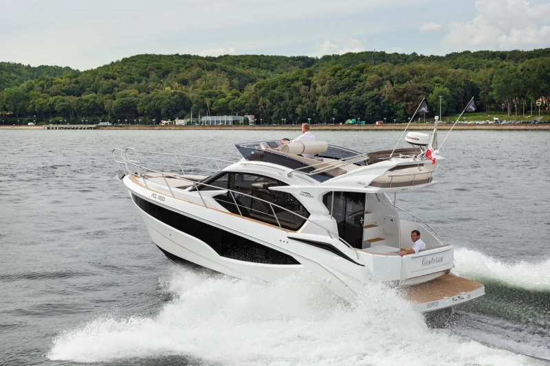 2025 Galeon 360 Fly yacht cruising on a scenic lake with lush green forest backdrop.