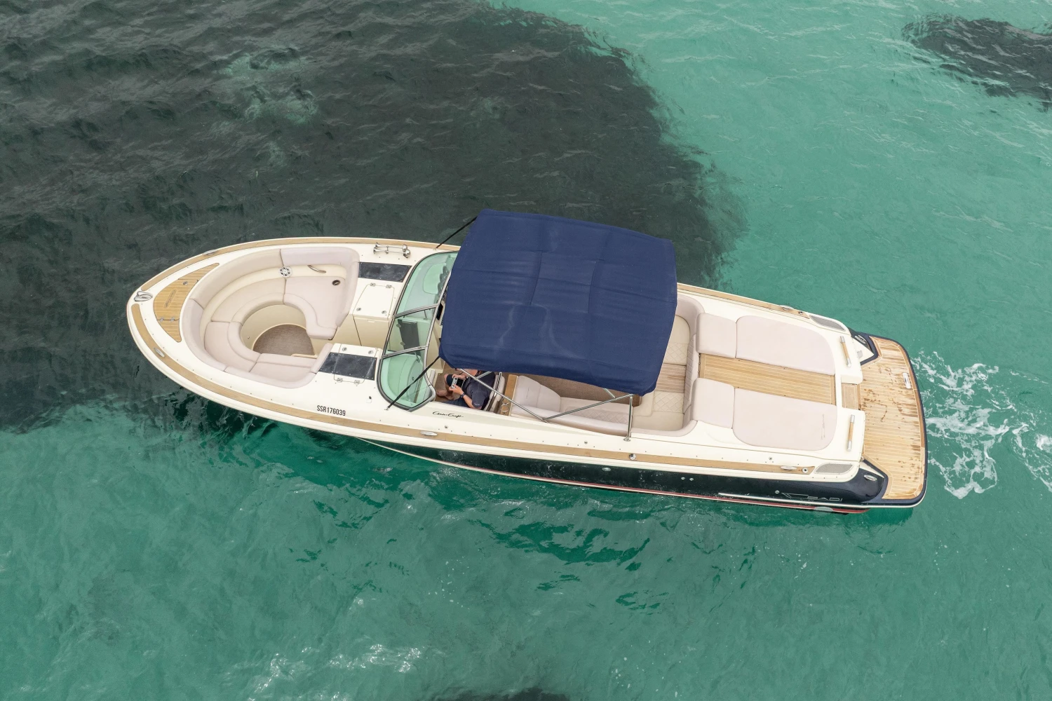 2013 Chris-Craft Launch 32 boat with blue canopy on turquoise water.