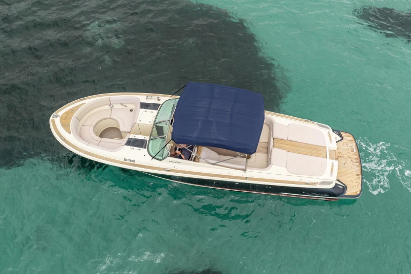 2013 Chris-Craft Launch 32 boat with blue canopy on turquoise water.