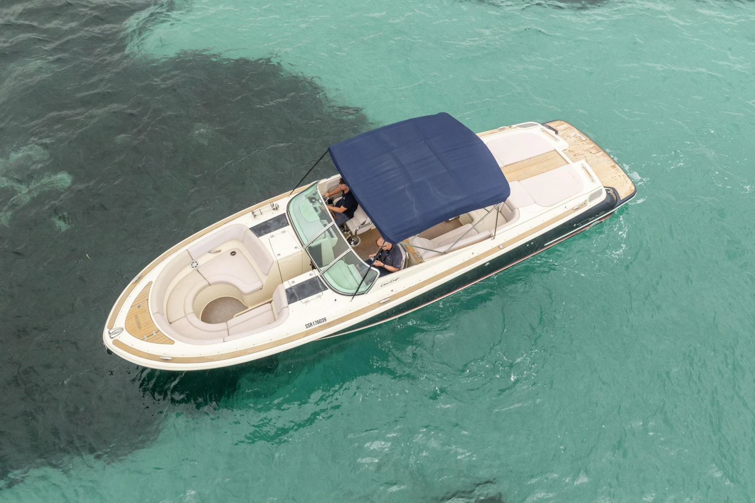 2013 Chris-Craft Launch 32 boat with blue canopy on clear turquoise water.