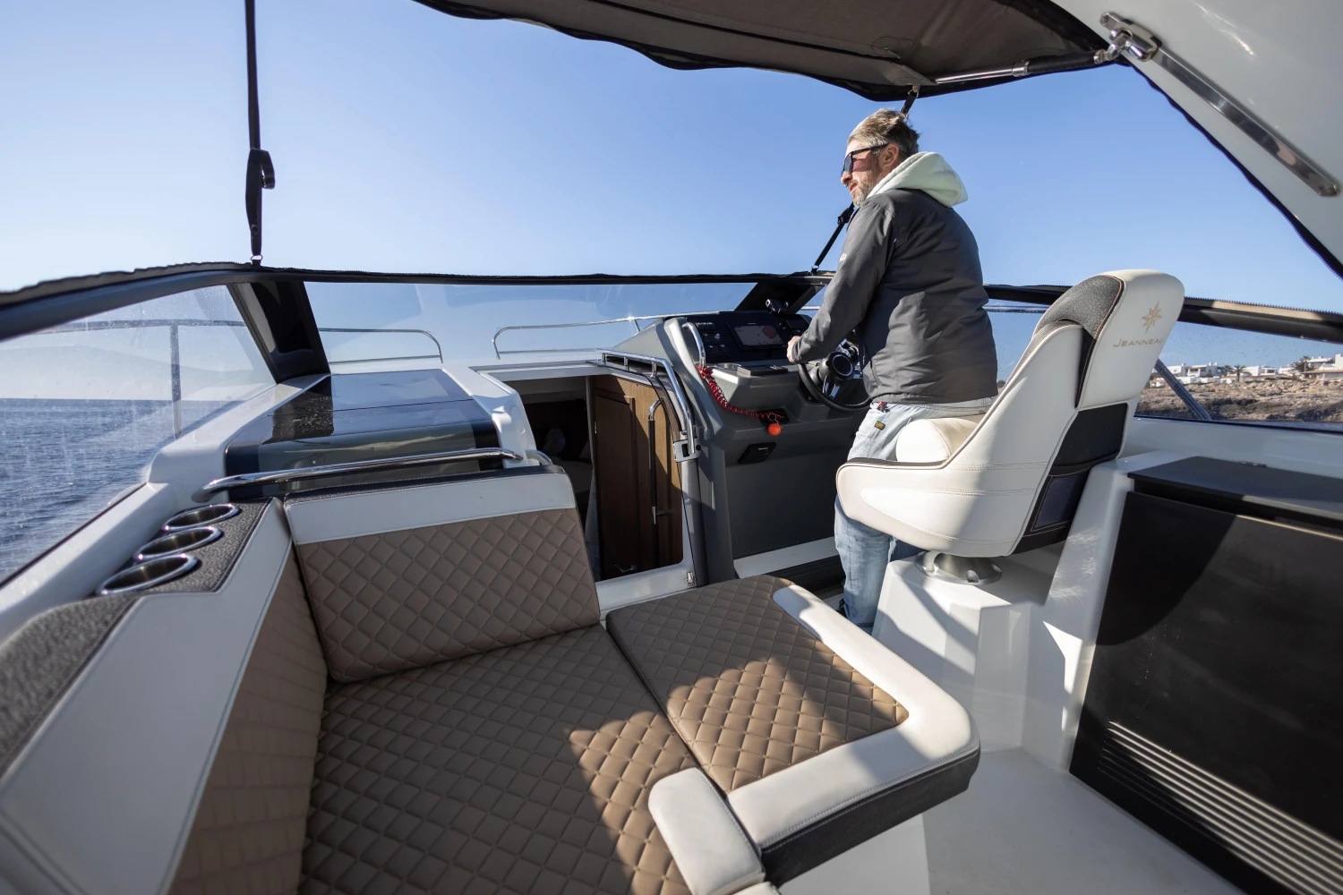 2018 Jeanneau Leader 30 boat interior with person at helm, featuring modern seating and controls.