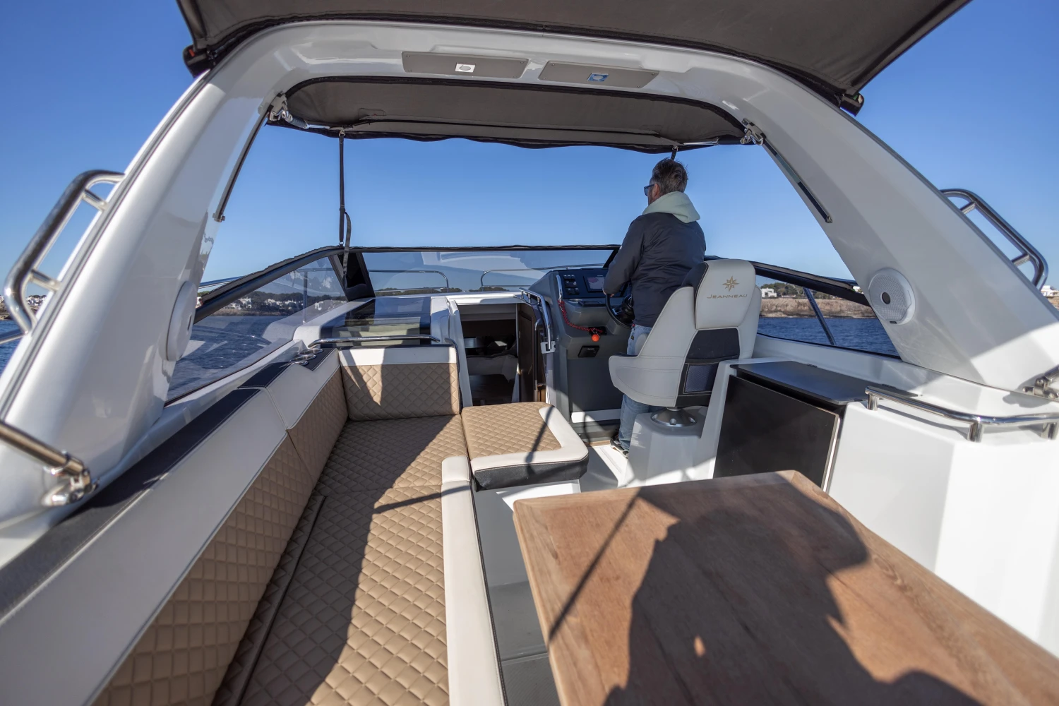 2018 Jeanneau Leader 30 yacht interior with seating, helm, and table on open water.