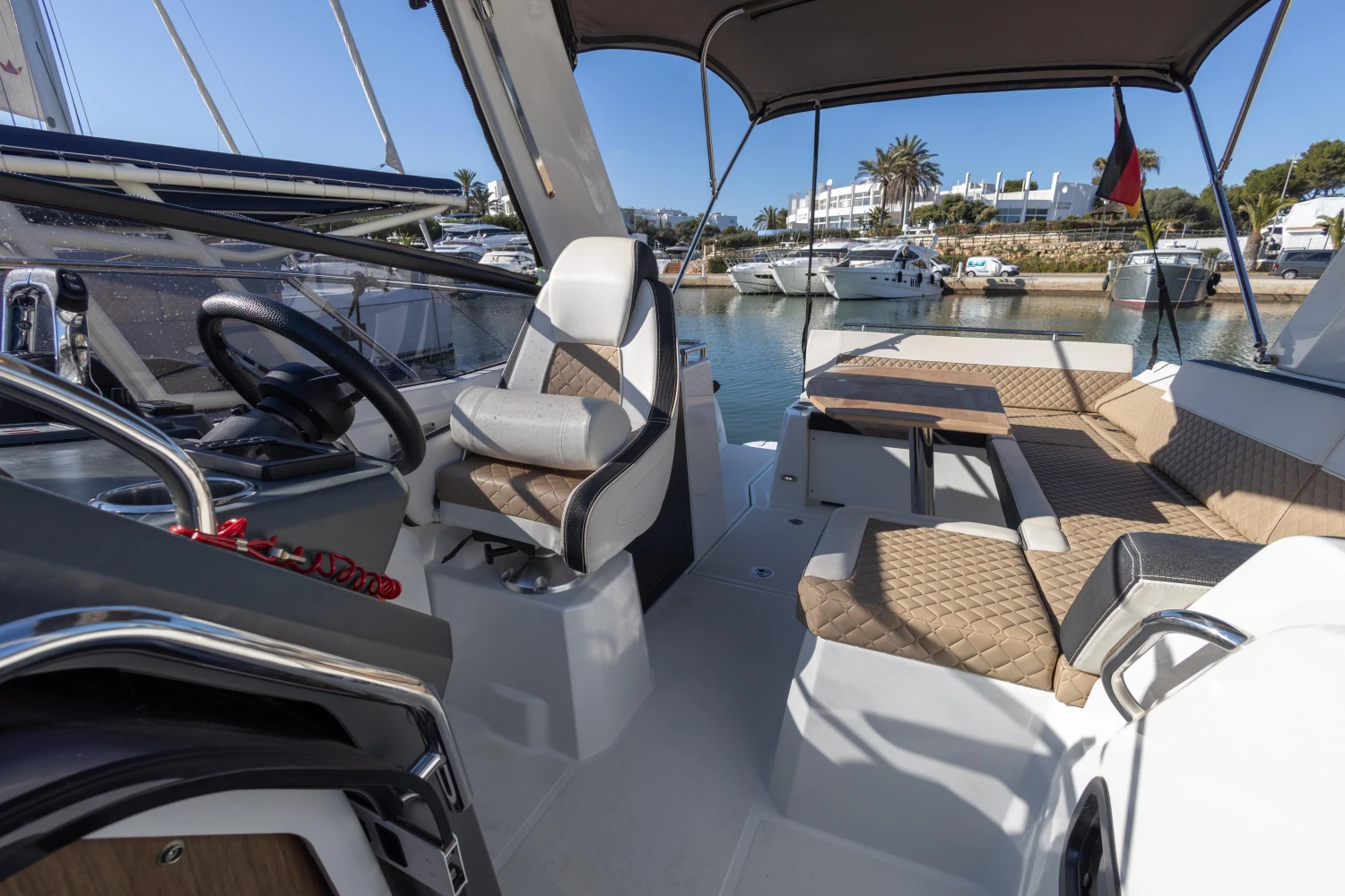 2018 Jeanneau Leader 30 interior with helm, seating, and table in a marina setting.