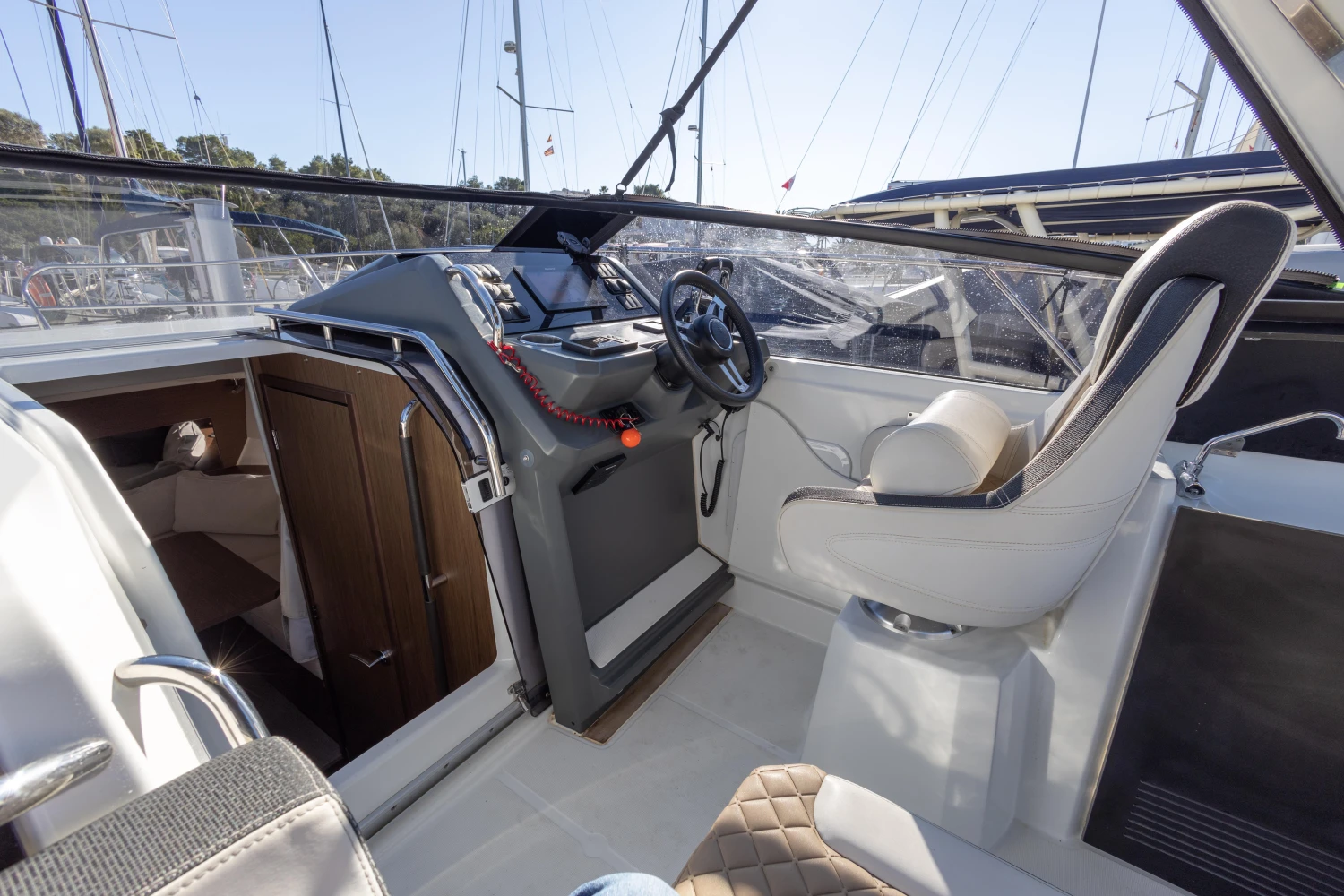 2018 Jeanneau Leader 30 cockpit with steering wheel and seating, docked at marina.