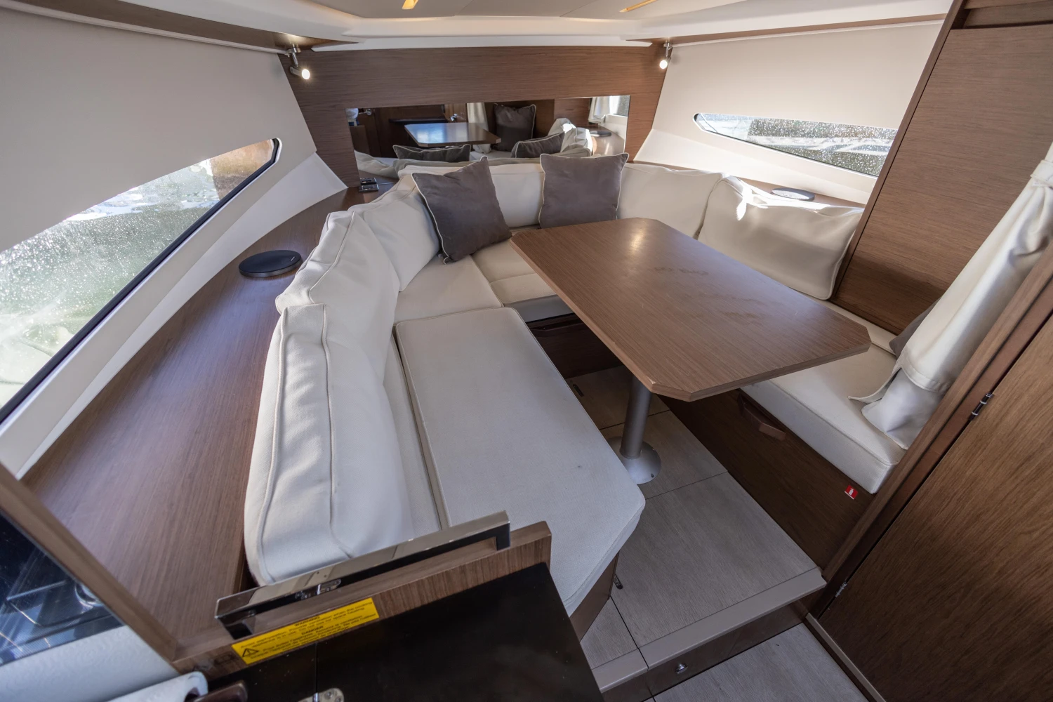 Interior of 2018 Jeanneau Leader 30 yacht with cozy seating and wooden table.